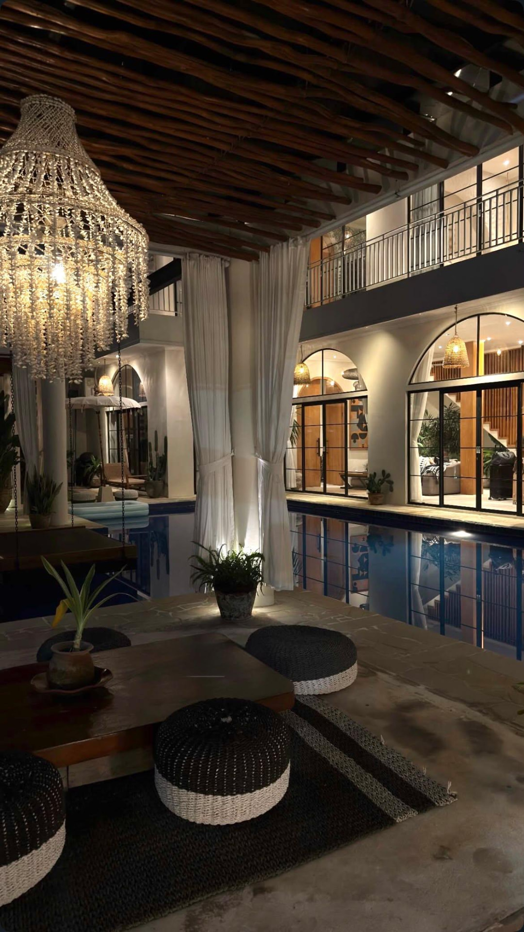 An intimate hotel lounge with a crystal chandelier, soft curtains and an indoor pool
