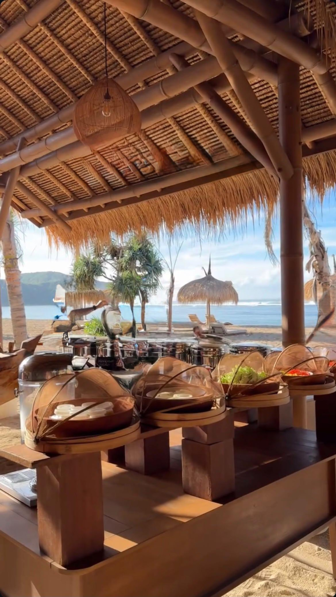 A beachside breakfast buffet under a thatched pavilion overlooking the ocean