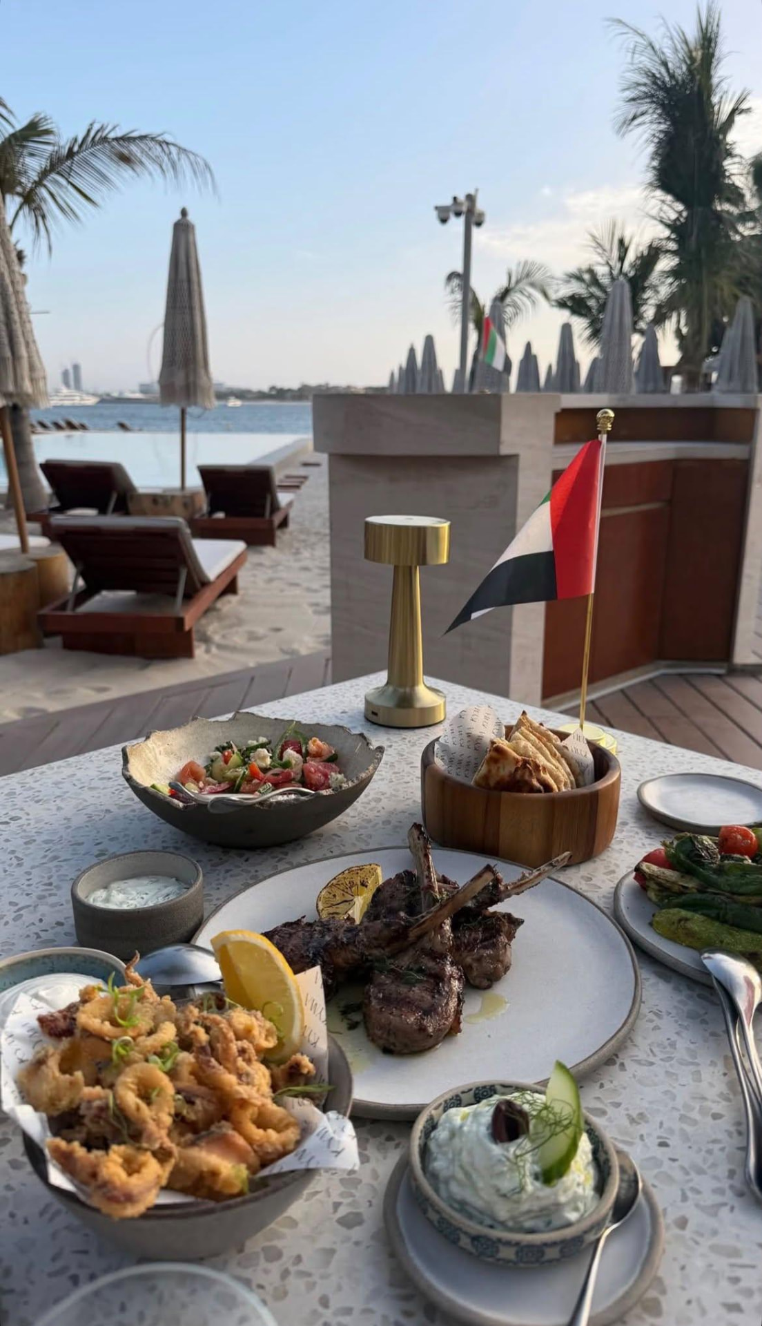A beautifully presented meal beside a resort pool with palm trees and ocean views