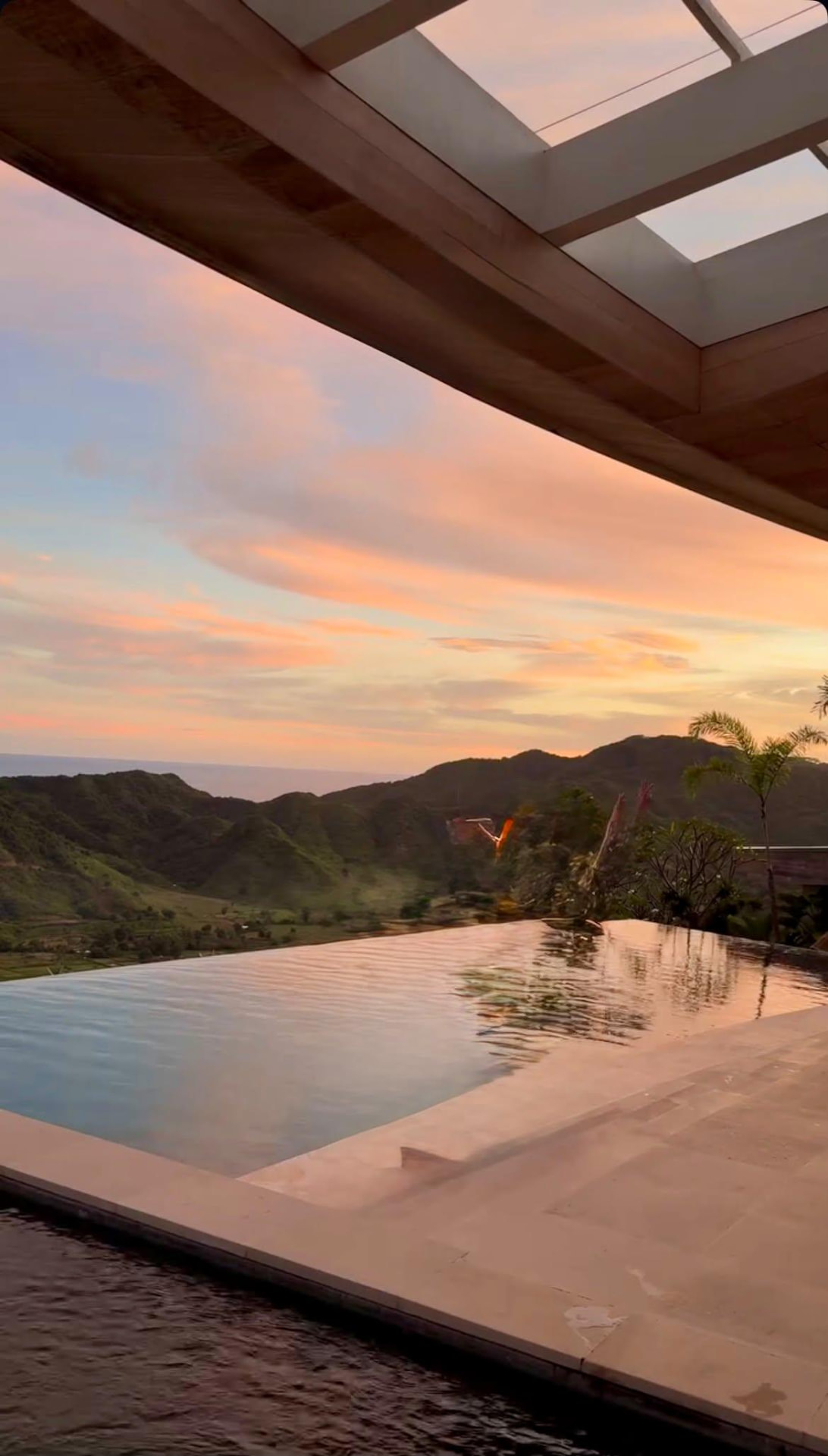 A hillside infinity pool reflecting a pink and lavender dusk over the valley