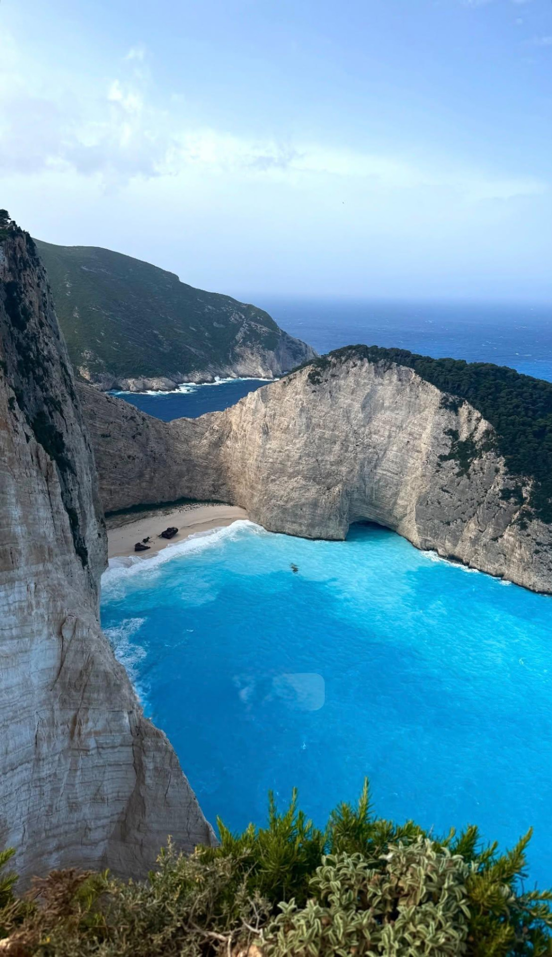 A turquoise bay and white-sand beach surrounded by dramatic coastal cliffs
